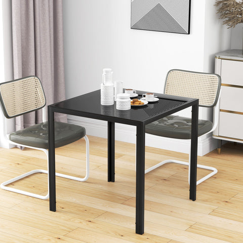 Black metal dining table with perforated top and white legs paired with cane back chairs for dinner parties