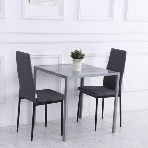 Gray glass-top dining table with powder coated steel legs and two gray upholstered chairs for dining room use