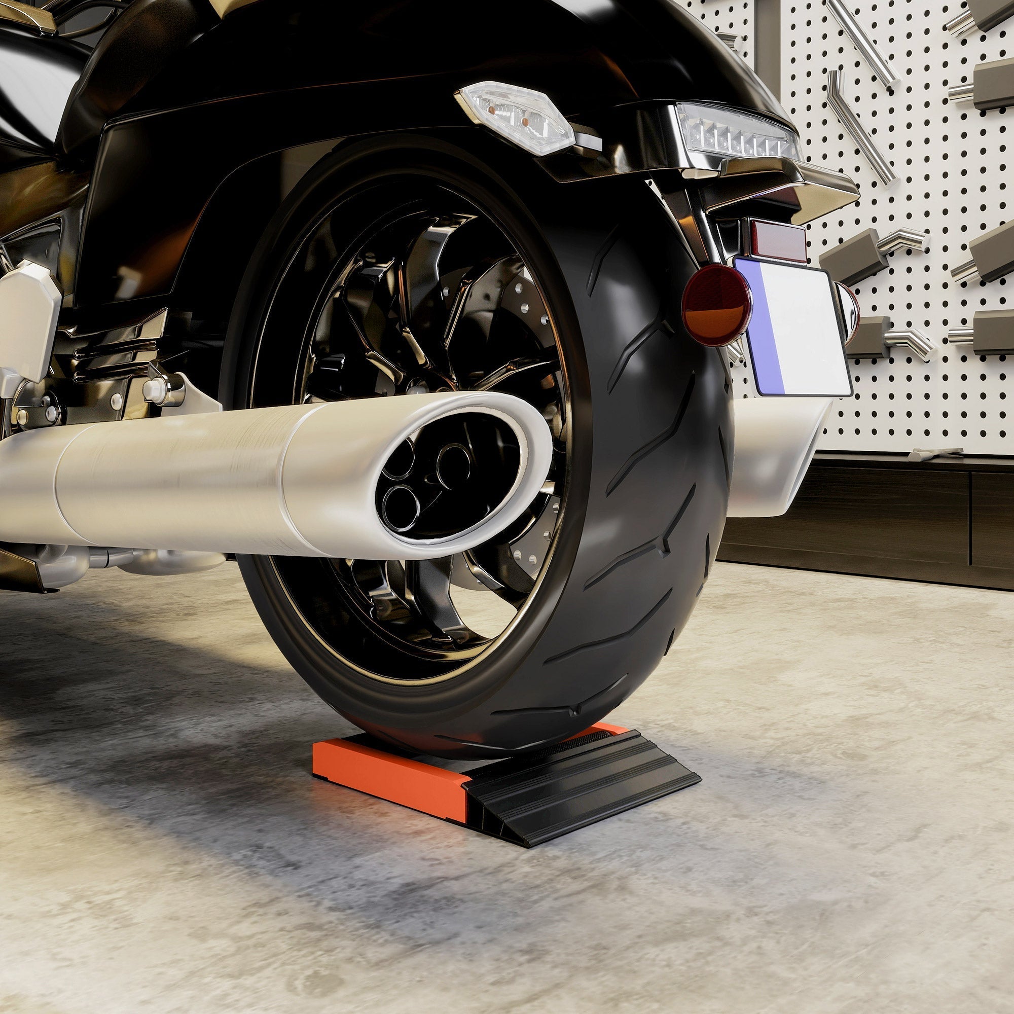 Black motorcycle wheel with chrome spokes resting on an orange and black aluminium alloy frame cleaning roller stand