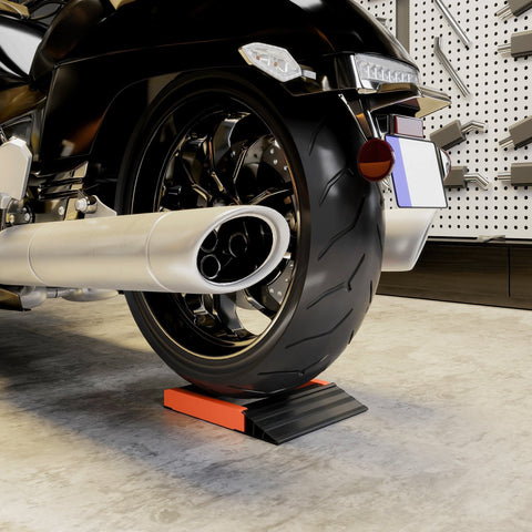 Black motorcycle wheel with chrome spokes resting on an orange and black aluminium alloy frame cleaning roller stand
