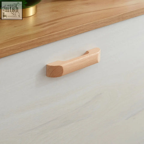 Light-colored wooden drawer handle with smooth finish on cream white particle board shoe storage cabinet for hallway use