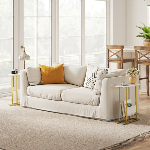Cream-colored sofa with mustard and black-and-white pillows next to a white marble grain end table with lower shelf