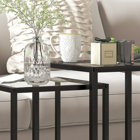 Clear glass vase with intricate cut crystal patterns placed on homcom black steel frame nesting tables with tempered glass top for living room