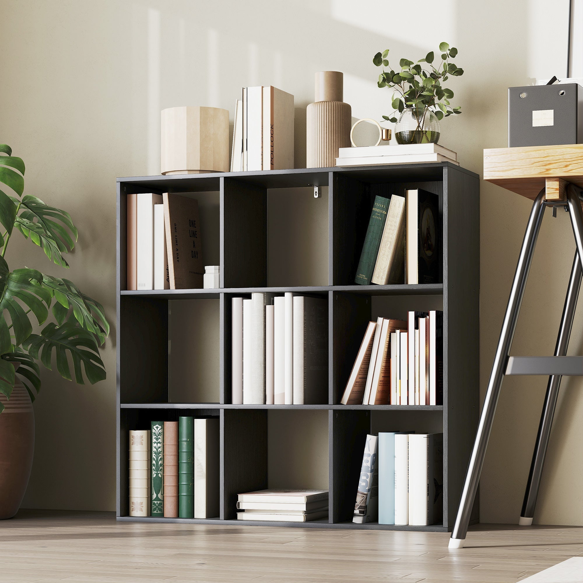 Modern black nine-cube modular bookshelf made of particle board with clean lines and colorful books in open cubbies