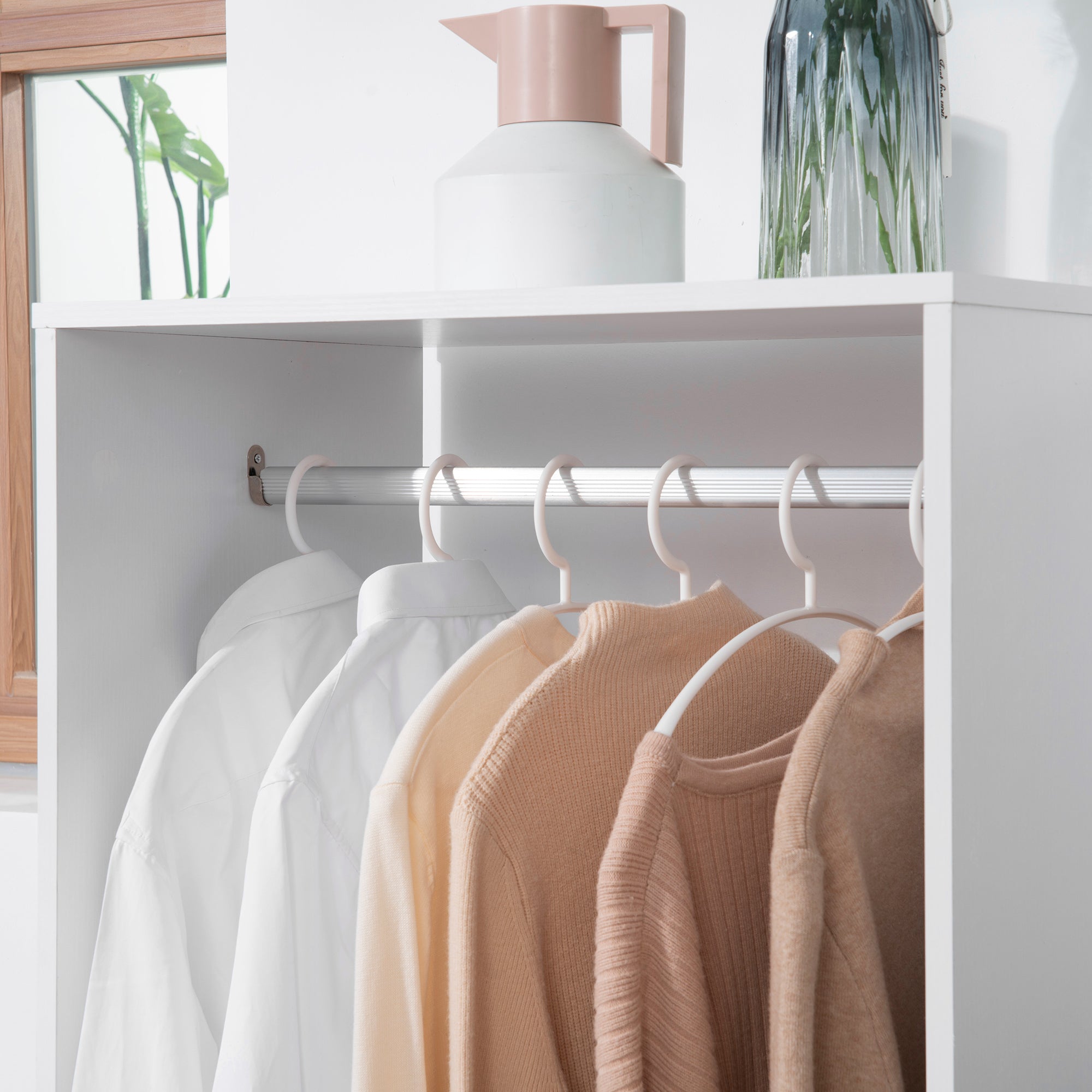 White metal homcom open wardrobe on wheels with aluminium hanging rail holding beige and white sweaters neatly arranged