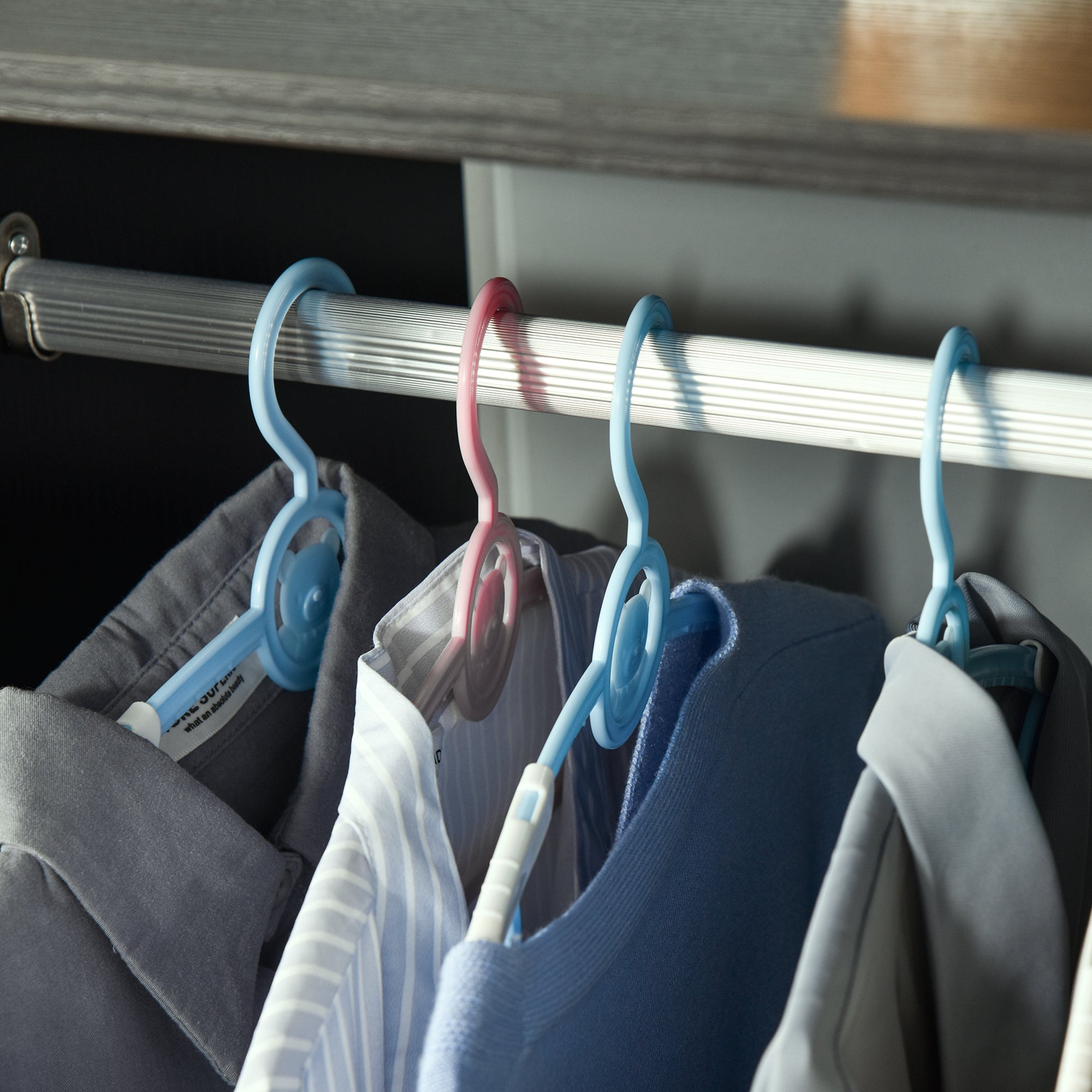 Light blue and pink plastic hangers with rotating design on aluminium hanging rail of homcom open wardrobe on wheels