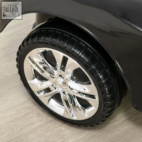 Chrome-finished multi-spoke alloy wheel with black tire on dark homcom ride on car baby walker with steering wheel and storage
