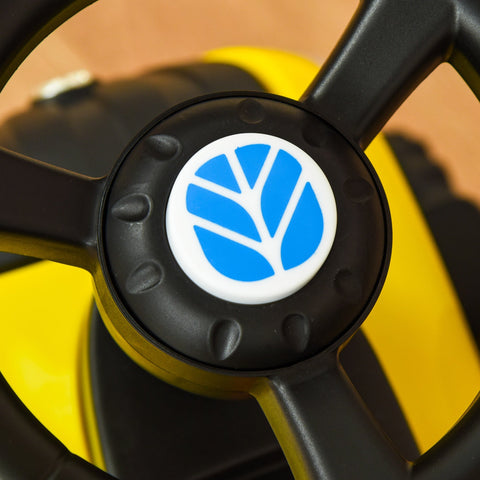 Black plastic steering wheel with blue and white emblem on homcom ride on tractor toddler walker with yellow cargo box