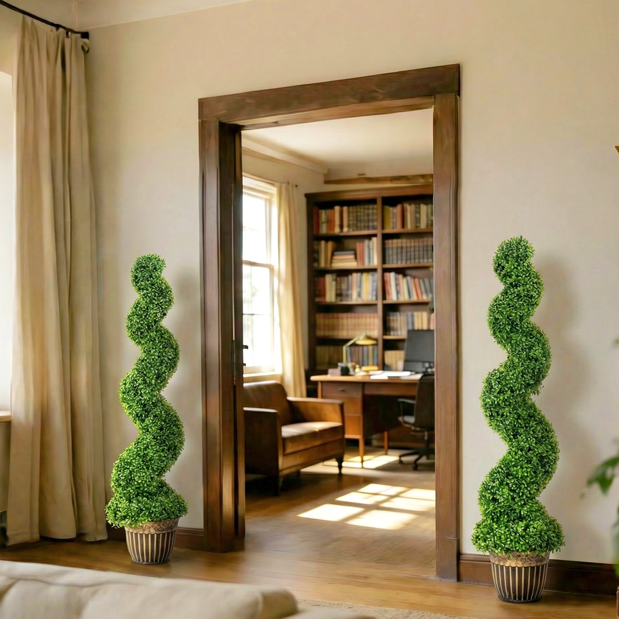 Two tall green spiral boxwood trees in striped ceramic pots flank a wooden doorway for indoor outdoor decor