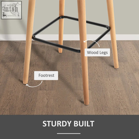 Modern bar stools with grey linen upholstery, solid wood legs, and a black metal footrest for dining or living room use