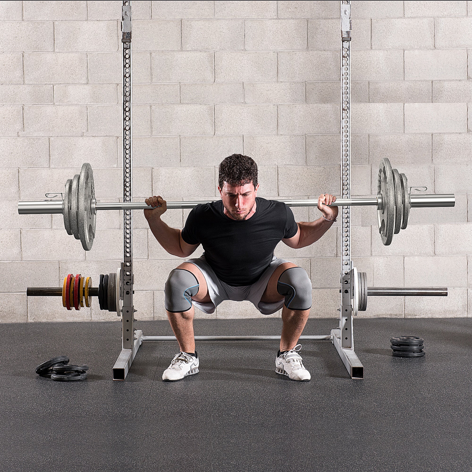 A man squats with a barbell on a power rack using homcom cast iron weight plates with a 2 inch centre hole