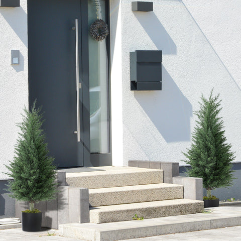Black modern mailbox mounted on white stucco wall next to homcom artificial cypress tree in nursery pot for green thumb decor