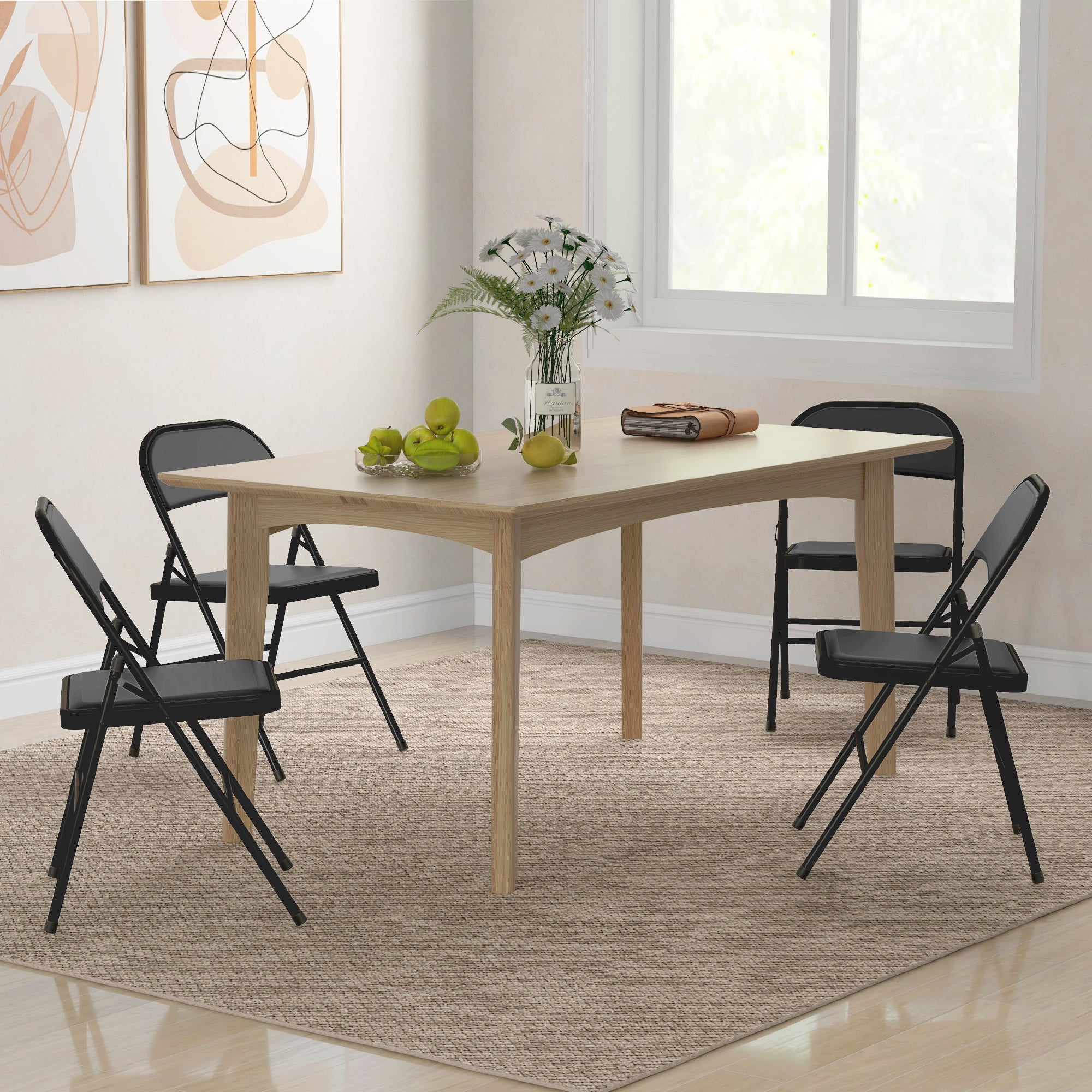Light wood rectangular dining table with four black cushioned folding chairs with steel frames around it
