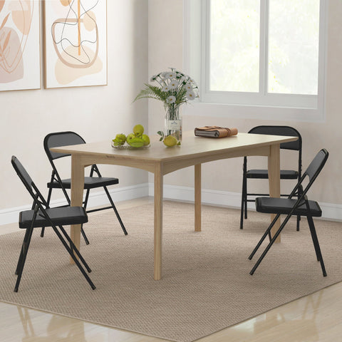 Light wood rectangular dining table with four black cushioned folding chairs with steel frames around it