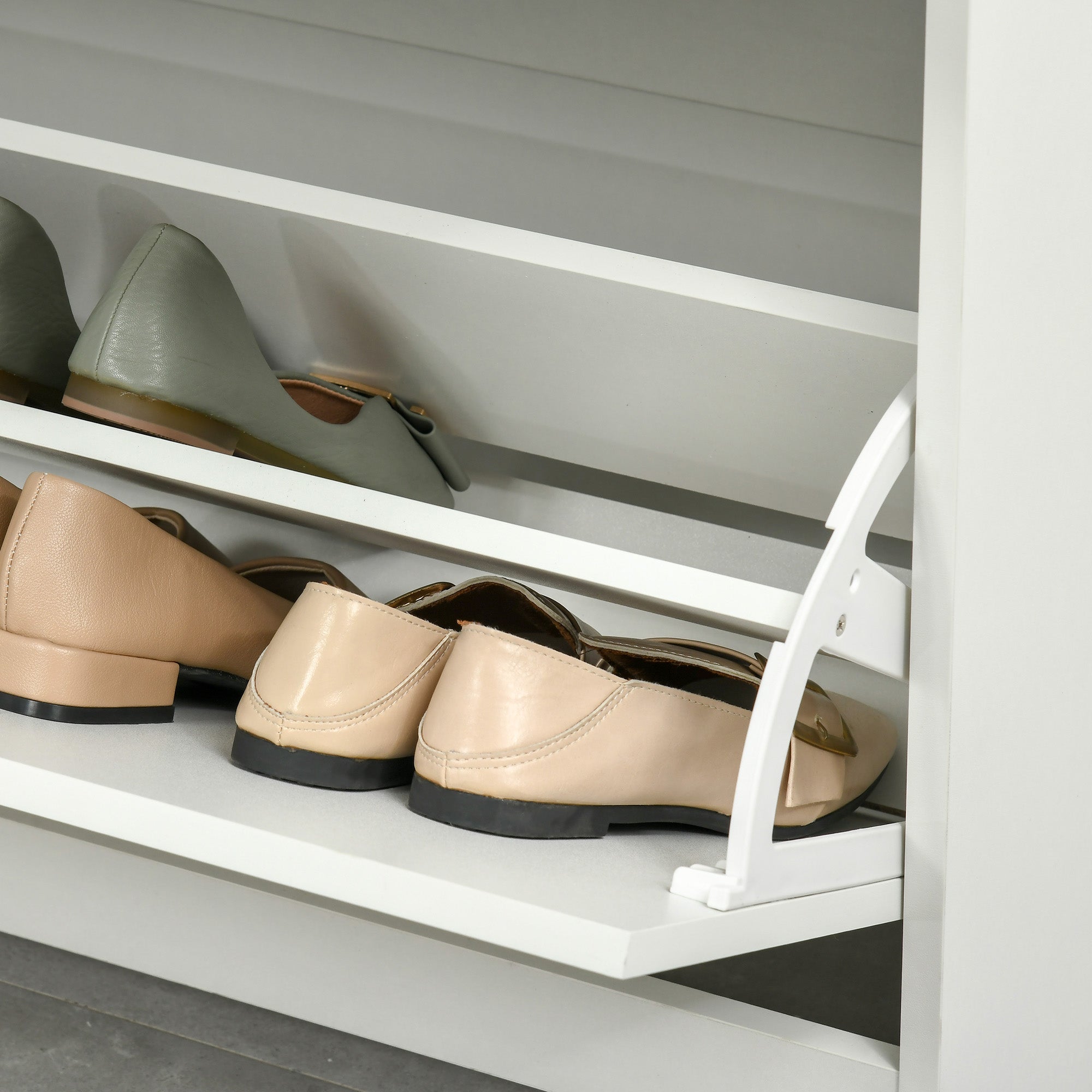 Beige leather loafers with black soles and gold-tone buckles displayed on a white homcom shoe cabinet with flip drawers and large storage