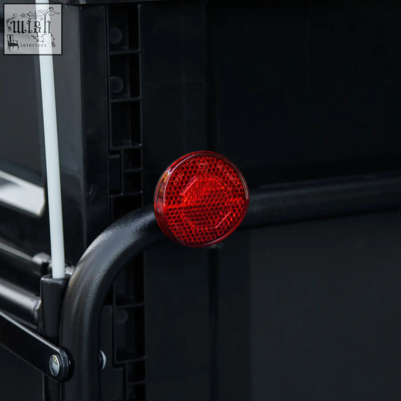 Red circular reflector with honeycomb texture on black metal frame at back of homcom steel bike cargo trailer storage box