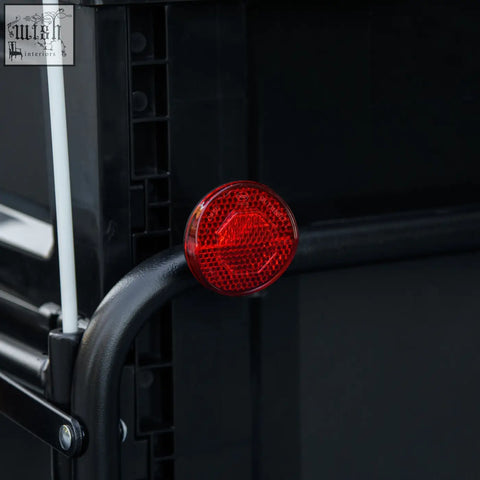 Red circular reflector with honeycomb texture on black metal frame at back of homcom steel bike cargo trailer storage box
