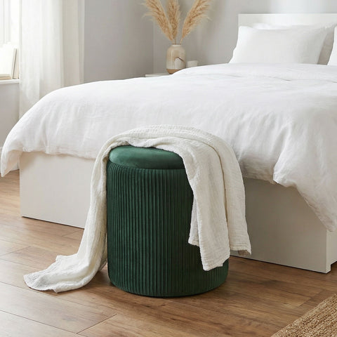 Deep green velvet storage ottoman with vertical ribbed texture and plush top perfect for living room use