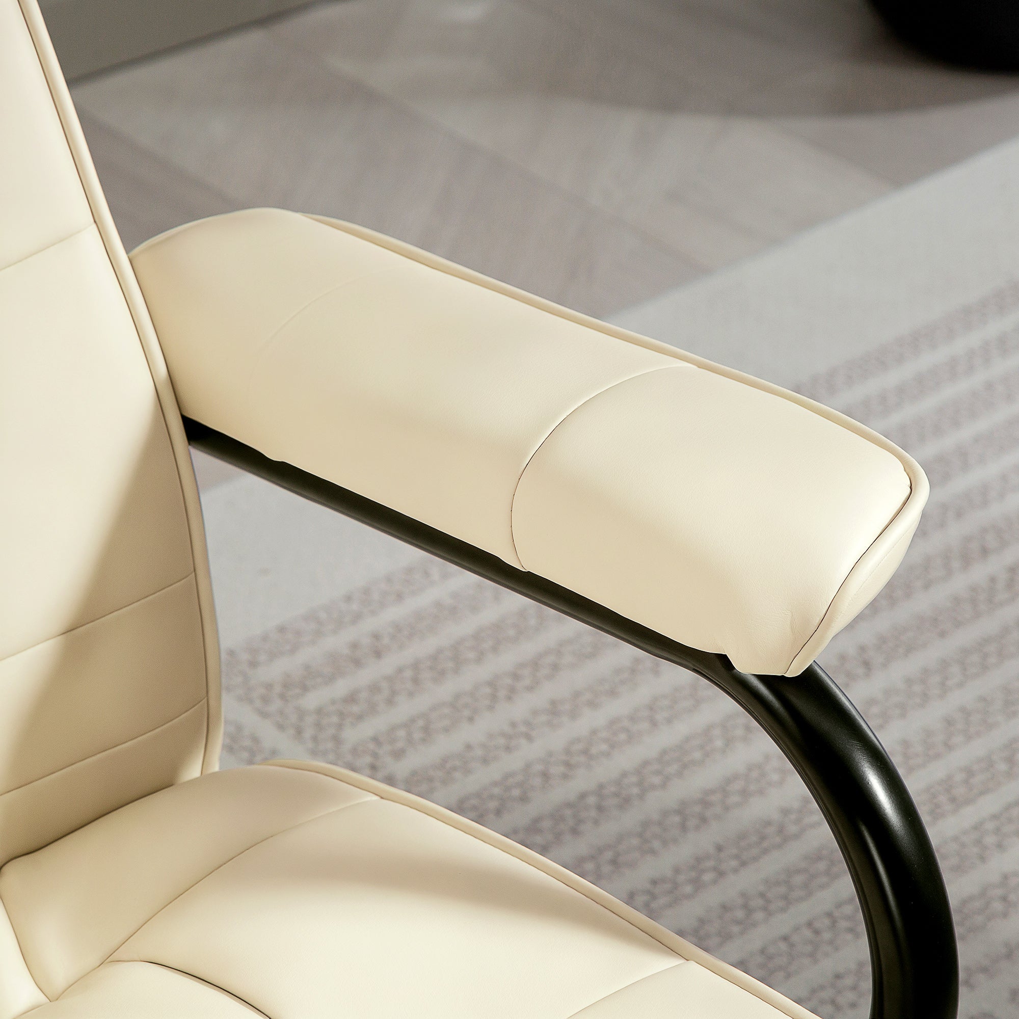 Cream white cream-colored leather armrest with sleek black metal frame on homcom swivel recliner chair with remote control