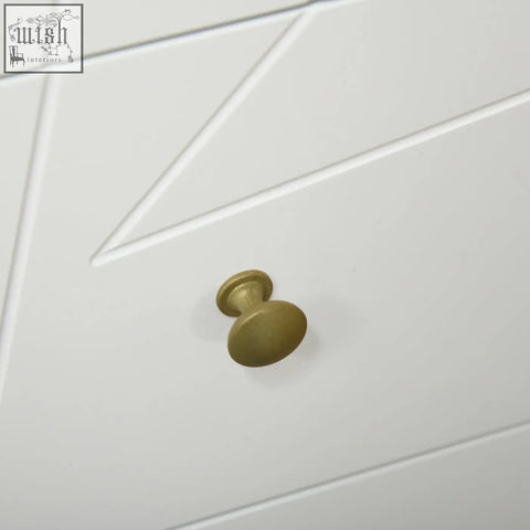 A matte brass cabinet knob with texture on a homcom white tall chest of drawers with hairpin-shaped metal legs