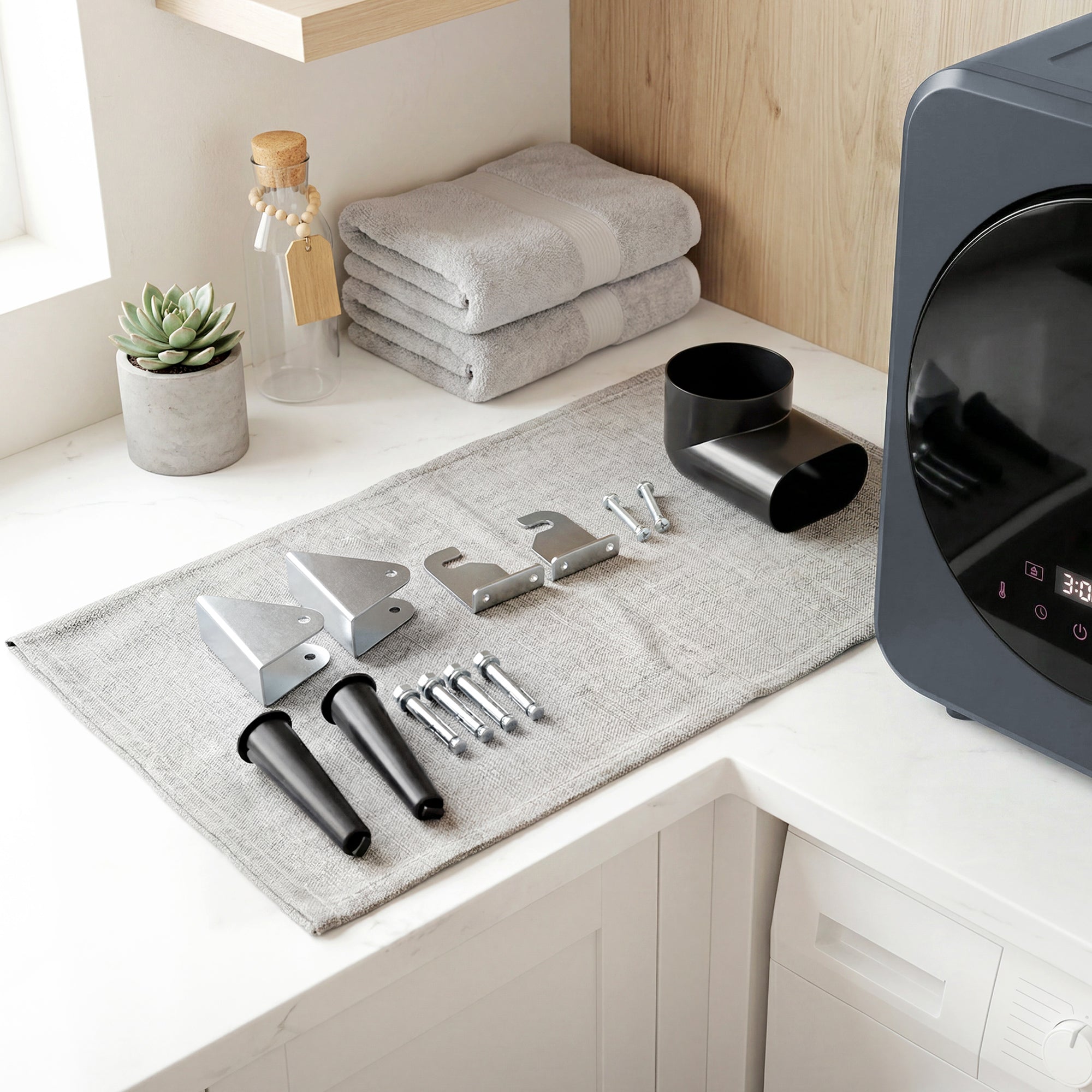 Gray homer vented tumble dryer with stainless steel tub and folded gray and white striped towels behind it