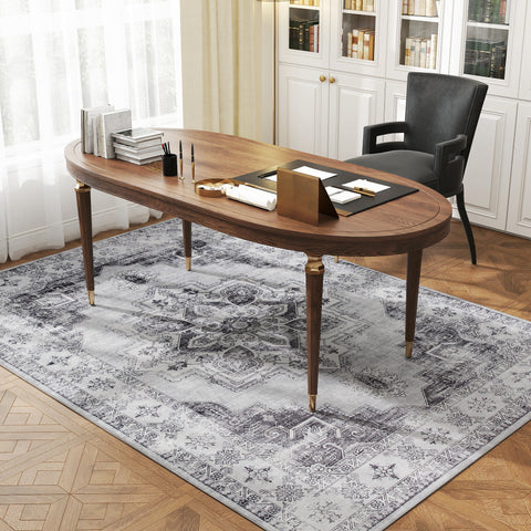 Elegant oval wooden desk with gold legs on a grey vintage-inspired floral area rug for living room or office use