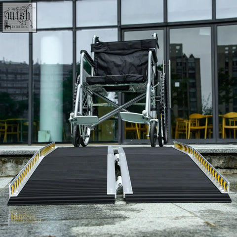 Silver-framed wheelchair on black folding aluminium alloy wheelchair ramp with yellow striped edges and non-skid surface