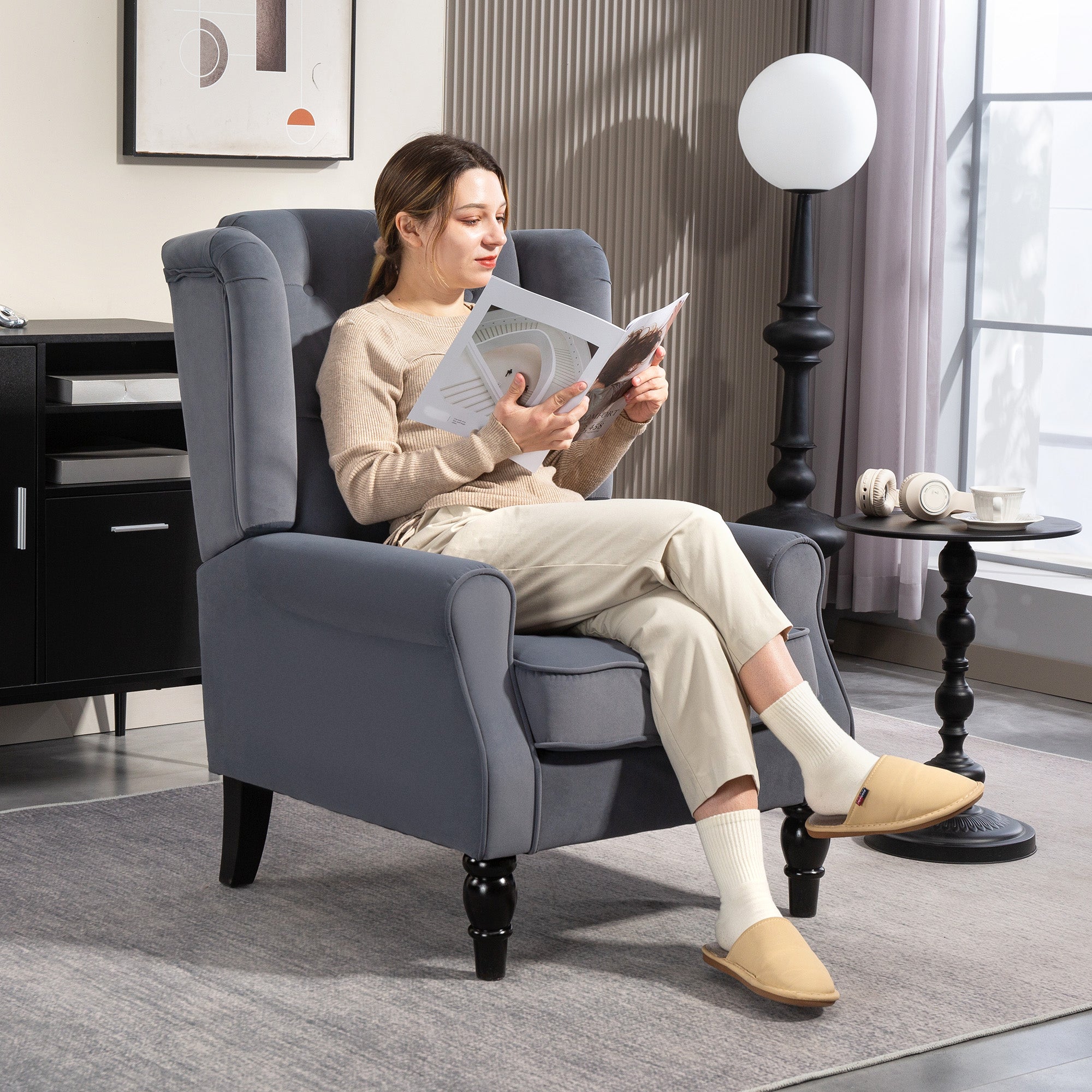 Gray upholstered wingback accent chair with button tufted back and black wooden legs at floor height for living room