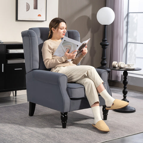 Gray upholstered wingback accent chair with button tufted back and black wooden legs at floor height for living room