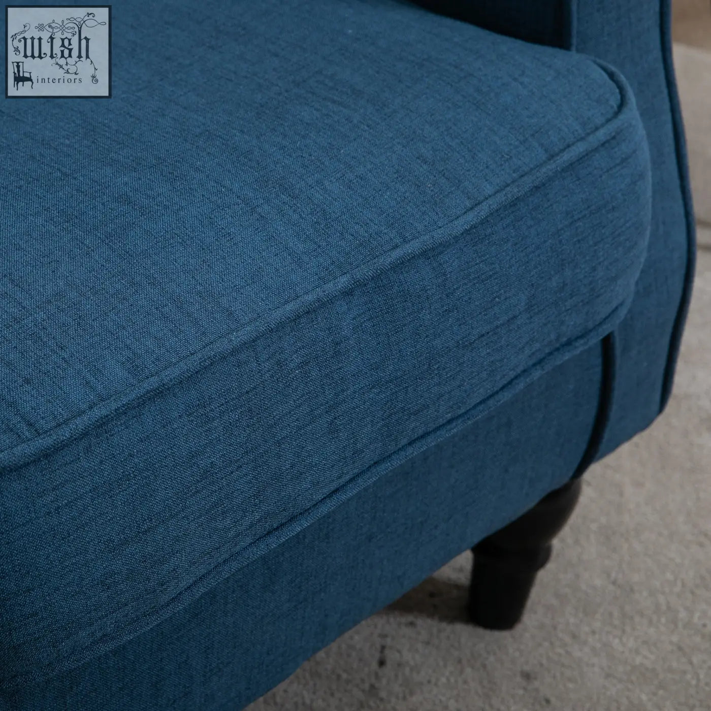 Deep blue wingback accent chair with textured fabric upholstery and dark wooden floor height legs for living room use