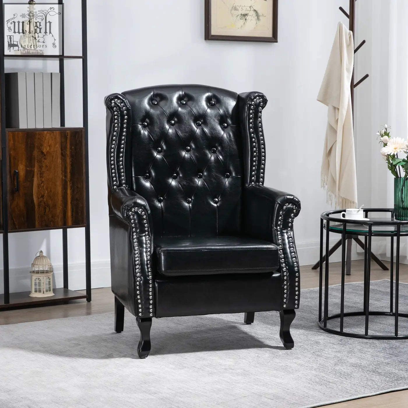 Black leather wingback armchair with tufted seat cushion and silver nailhead trim on eucalyptus wood frame for living room