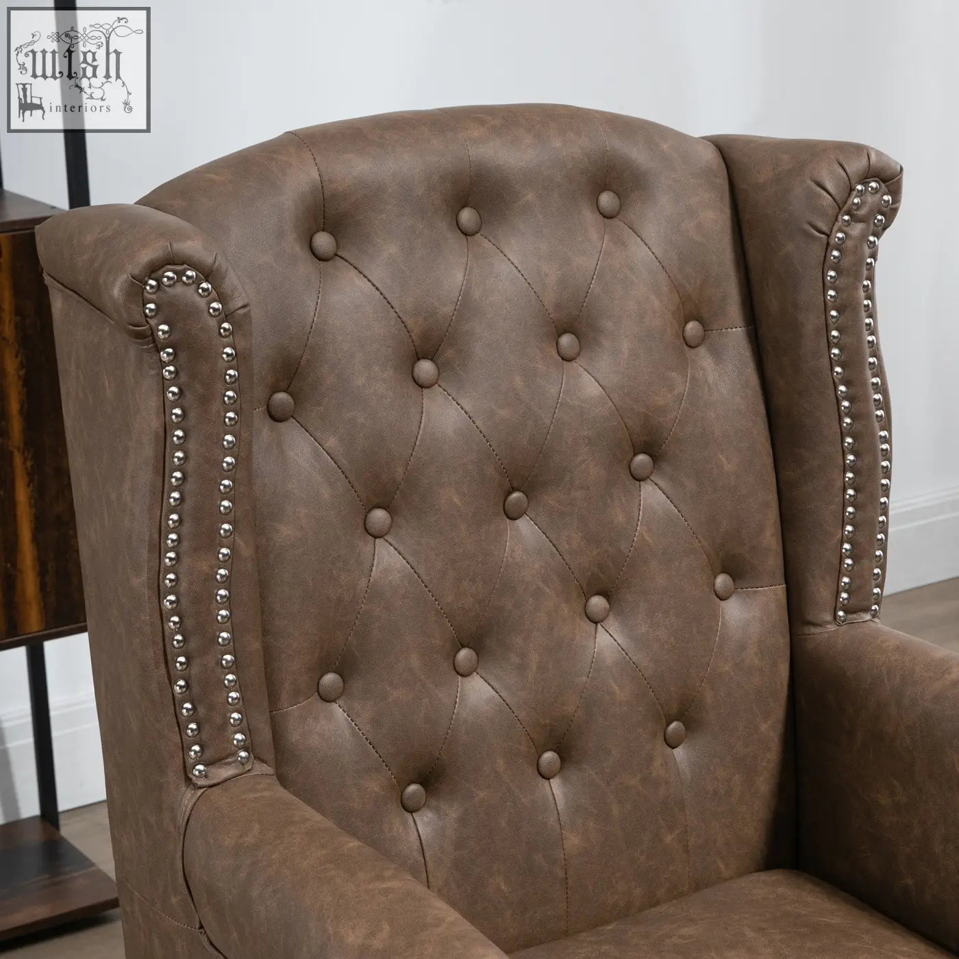 Brown tufted leather wingback chair with nail head trim and soft seat cushion for living room or bedroom use