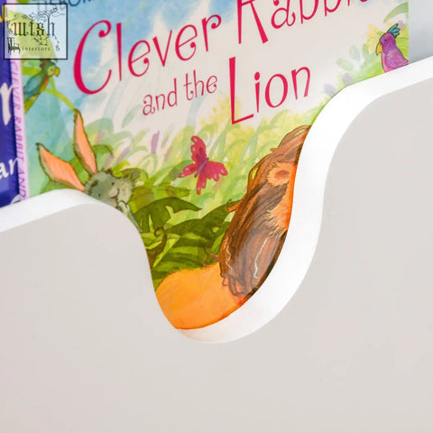 White wooden kids toy box with curved book slot holding clever rabbit and the lion book features gas hinge storage box