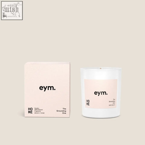 A minimalist white glass standard candle with a soft pink eym label and matching blush box called the grounding one