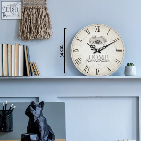 A round off-white home sweet home wall clock with black roman numerals and decorative script design
