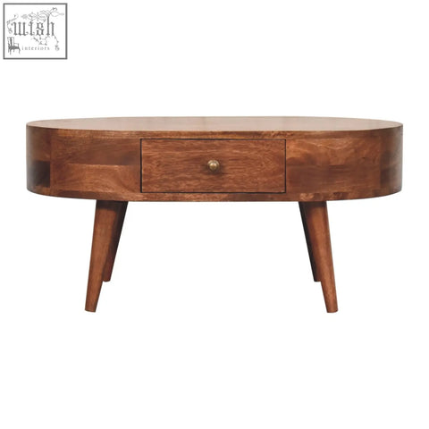 A sleek oval coffee table with honey caramel finish made of dark brown wood featuring a drawer and tapered legs