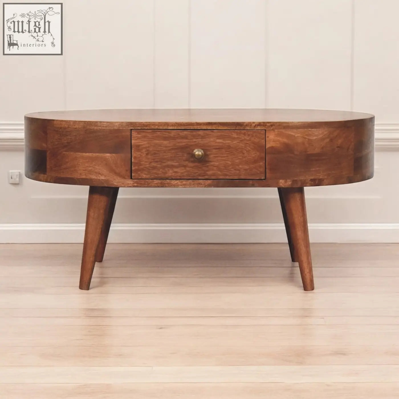 A sleek oval coffee table with tapered legs and a rich honey caramel finish in dark wood