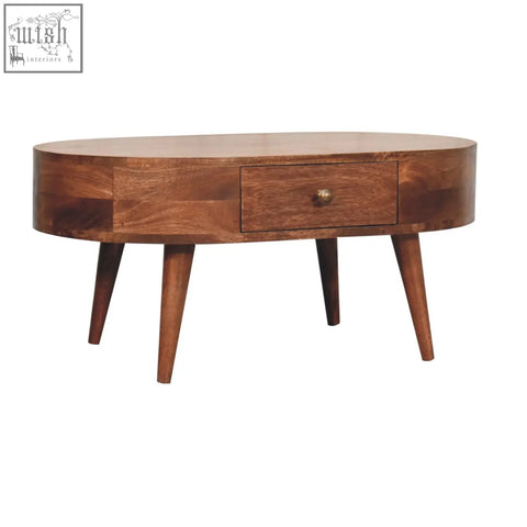 A warm brown honey caramel coffee table with an oval shape, single drawer, and tapered legs in honey caramel finish