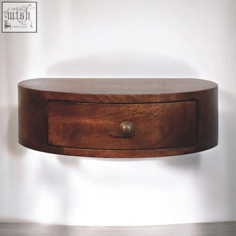 A sleek oval wooden honey caramel finish wall-mounted rounded bedside table with a single drawer and brass knob