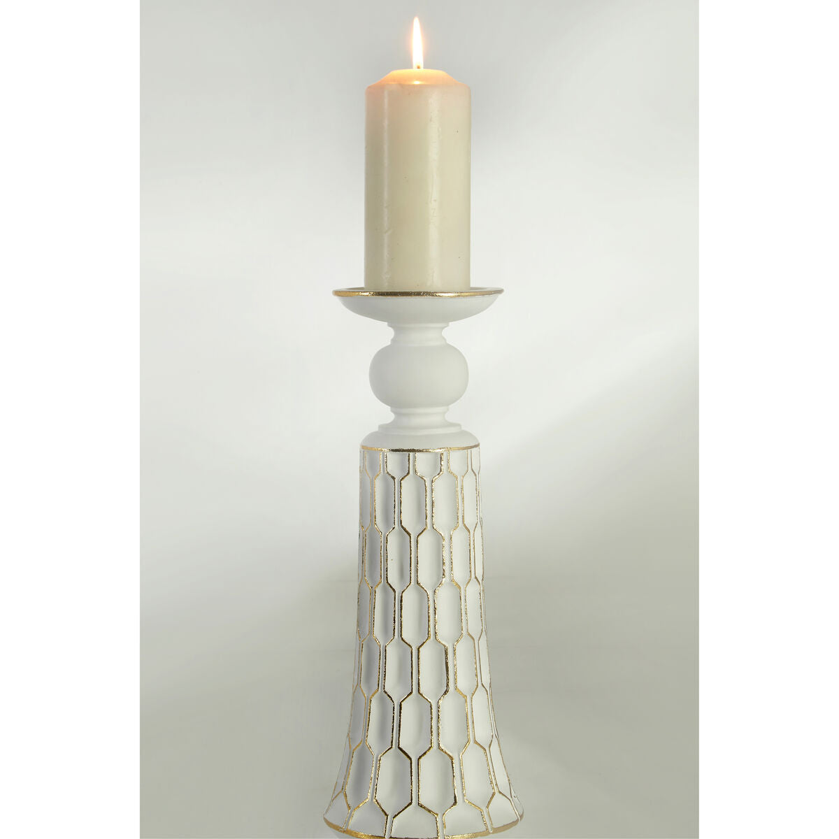 White small candle holder with gold geometric honeycomb pattern holding a cream-colored taper candle