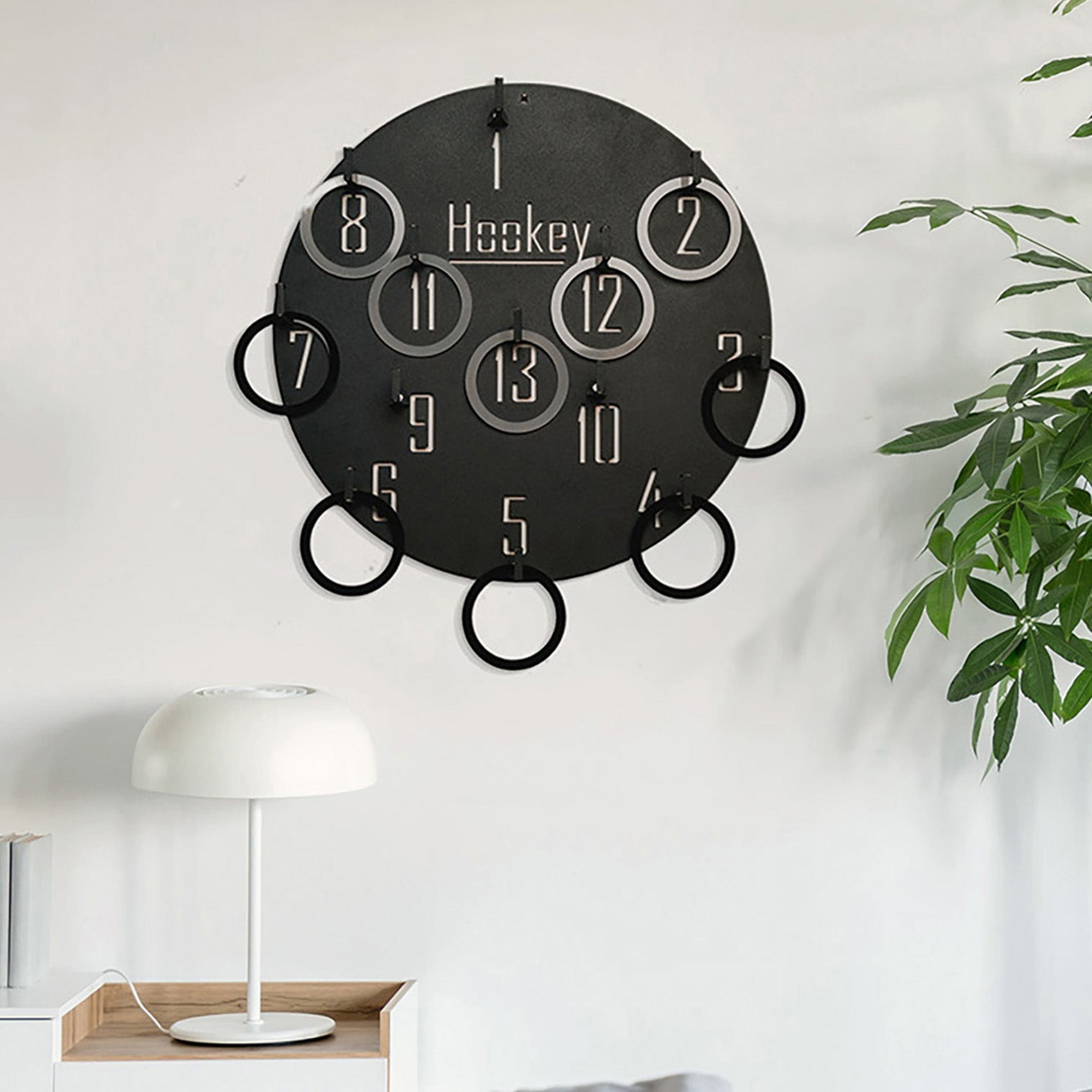 Black circular wall game clock with metallic numbers and hanging rings featuring hockey word for all age range