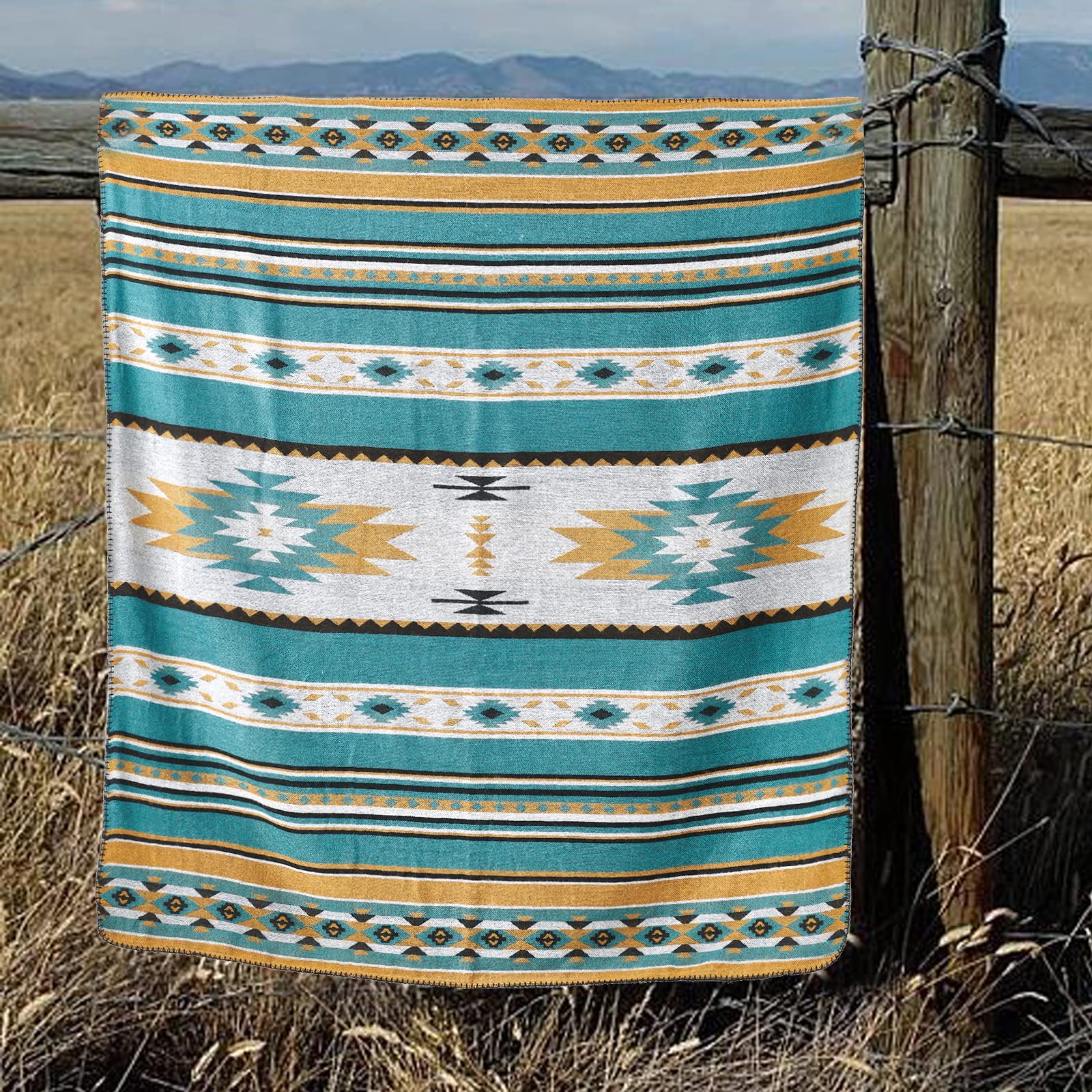 A teal and gold horimote home aztec soft sherpa throw blanket with tribal patterns hanging on a wooden fence post