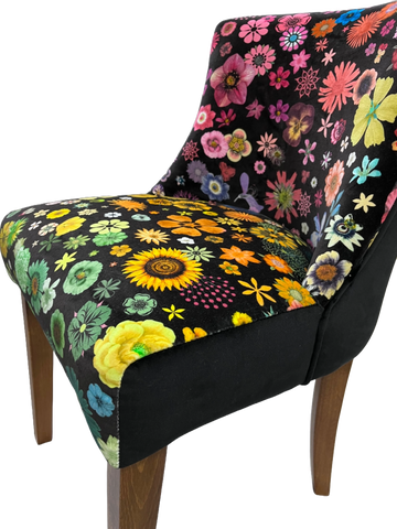 A vibrant floral-patterned horton chair upholstered in plush black velvet with pink yellow green and blue flowers