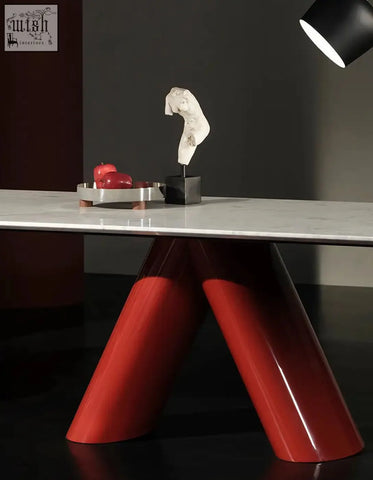 A sleek red hossain dining table with a white marble top and angular v-shaped legs perfect as a marble dining table