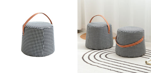 Black and white houndstooth round footstool with a tan leather handle and cylindrical shape for stylish seating