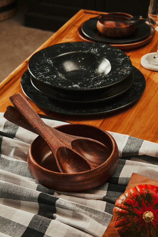 A rich dark brown wooden black pasta bowl with smooth finish and two matching spoons inside perfect for pasta meals