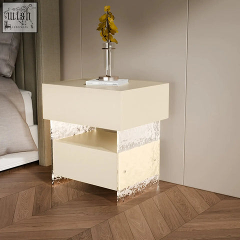 Cream-colored ibarra bedside table with glossy finish and textured metallic silver accents on lower edges and light strip