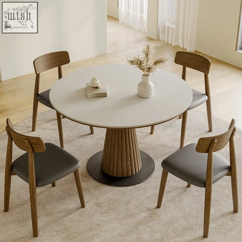 Round ichiro dining table with white tabletop and fluted wooden pedestal base with four dark gray upholstered chairs
