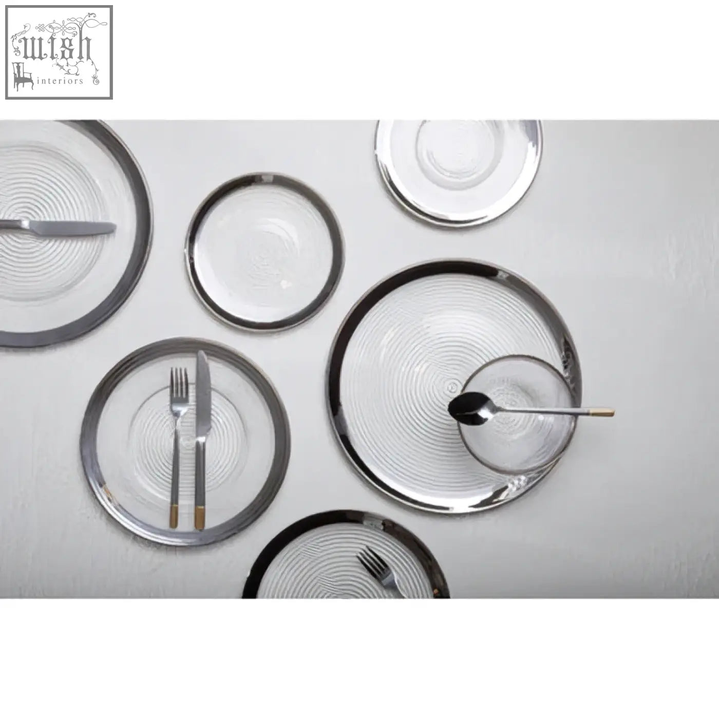 Set of modern glass coupe charger plates with silver rims and subtle concentric circular patterns