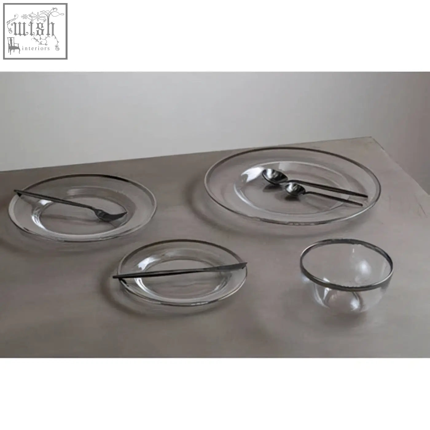 Clear glass charger plate with sleek silver rim paired with matching black utensils for stylish dining